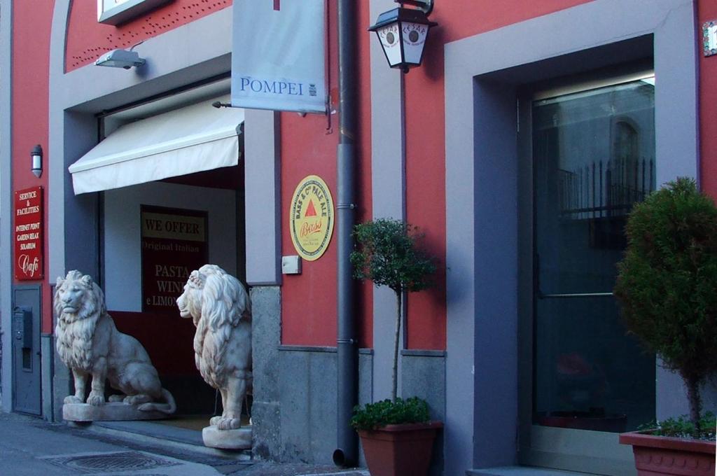 due statue di leoni davanti a un edificio di Agorà Hostel a Pompei