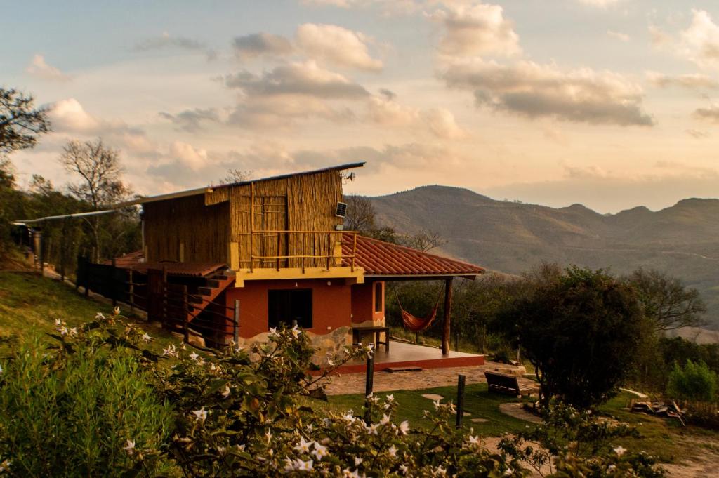 una casa en una colina con montañas en el fondo en Cabaña Los Guapurús, en Samaipata