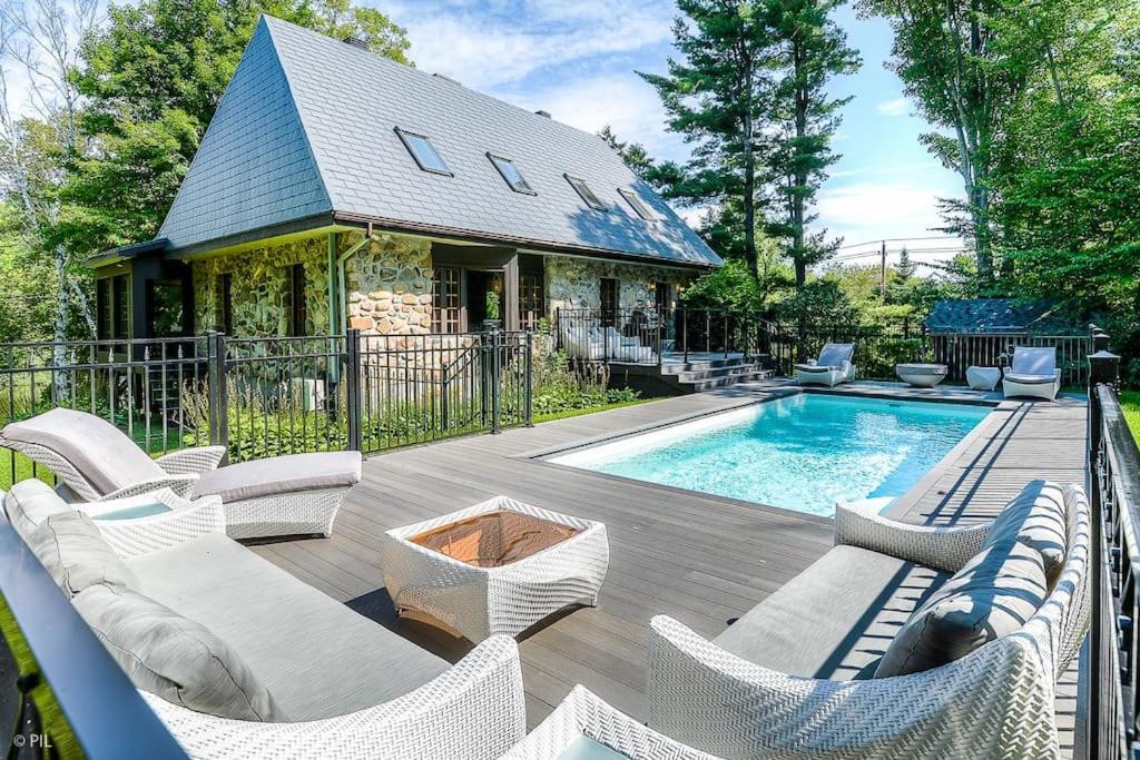 un cortile con piscina, sedie e una casa di Panorama a Sainte Anne des Lacs