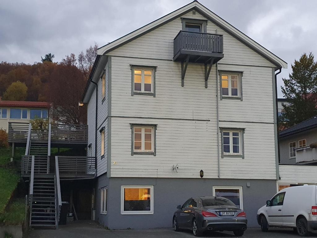 a large white house with a car parked in front of it at Åsveien Apartments. in Harstad