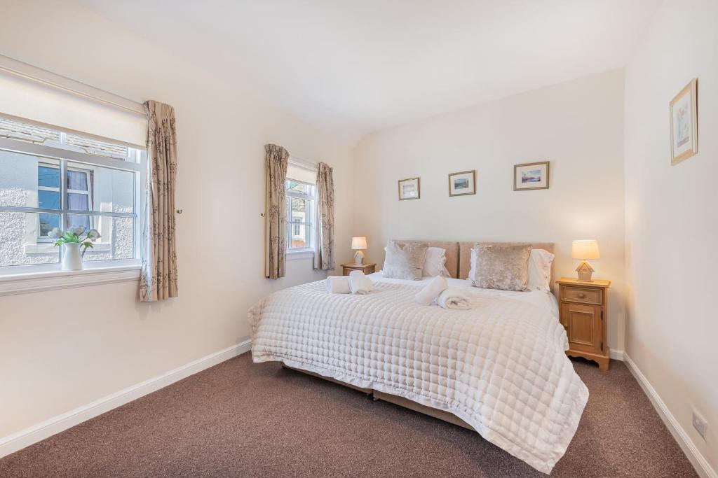 a white bedroom with a bed and a window at Cottage 9 Old Farmhouse Braithwaite in Keswick