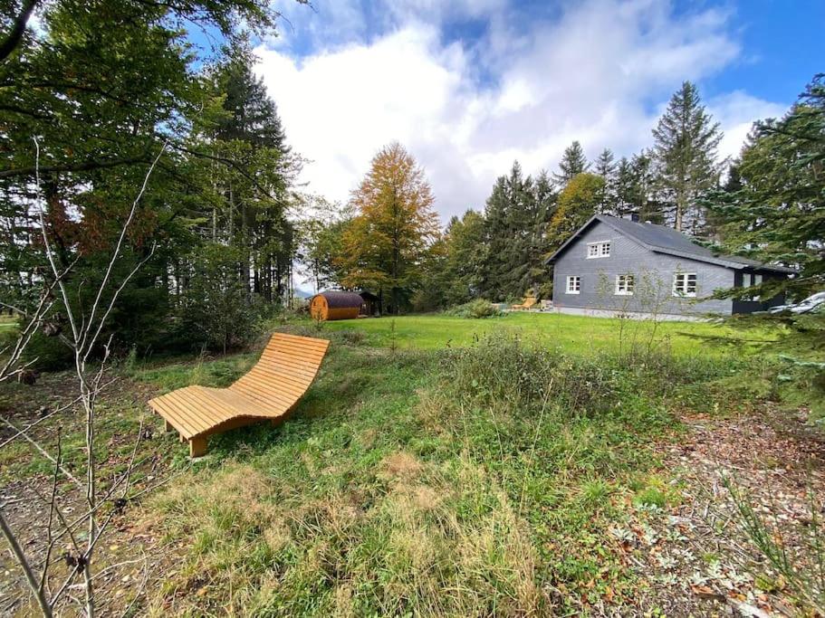 a bench sitting in the grass in front of a house at Ferienhaus Asten-Lodge in Winterberg