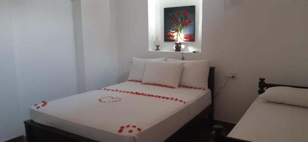 Sun Kiss lagoon bentota في بينتوتا: غرفة نوم صغيرة مع سرير أبيض بقلوب حمراء عليه