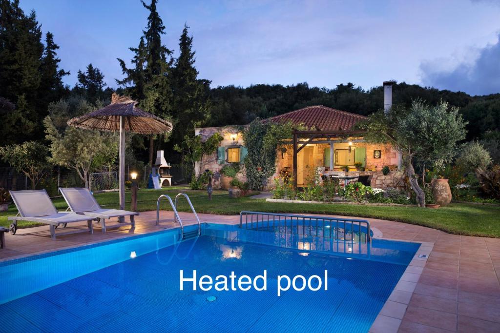 a backyard with a heated pool and a house at Boutique Villa Petra Eleni in Fílippos