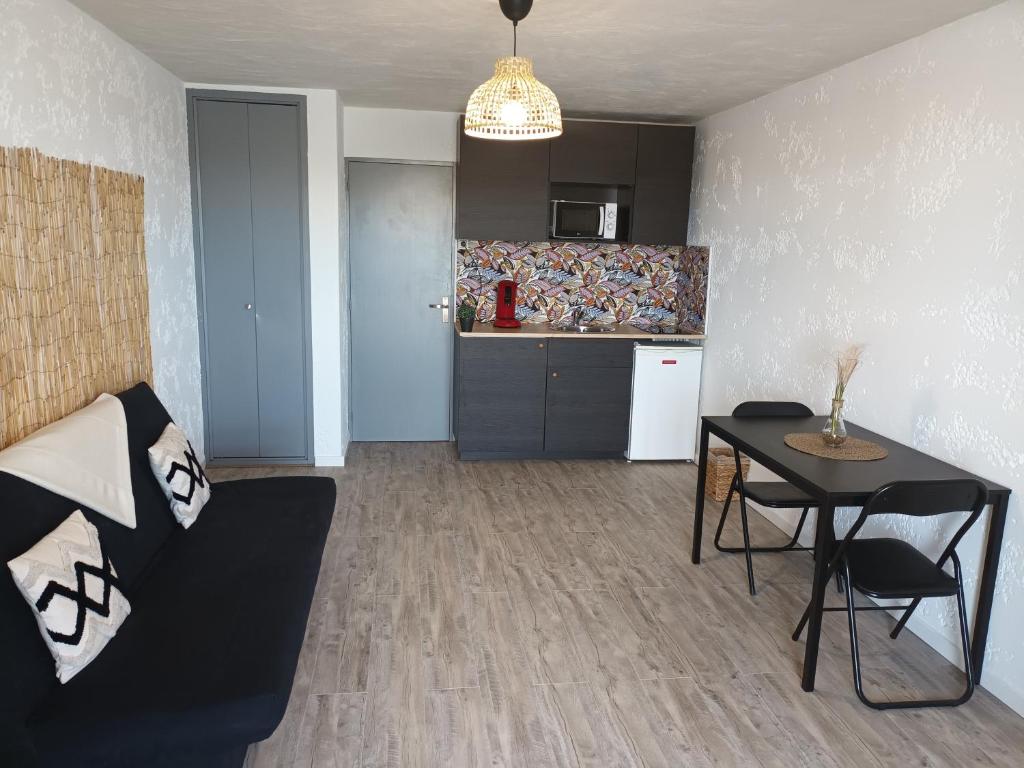ein Wohnzimmer mit einem Sofa und einem Tisch sowie eine Küche in der Unterkunft Studio spacieux plage in Fos-sur-Mer