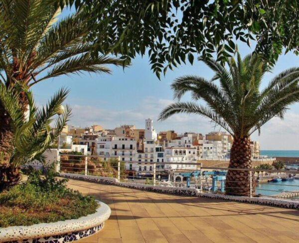 eine Stadt mit Palmen und Gebäuden und dem Meer in der Unterkunft Precioso piso, todo equipado a 300m de las playas in L'Ametlla de Mar