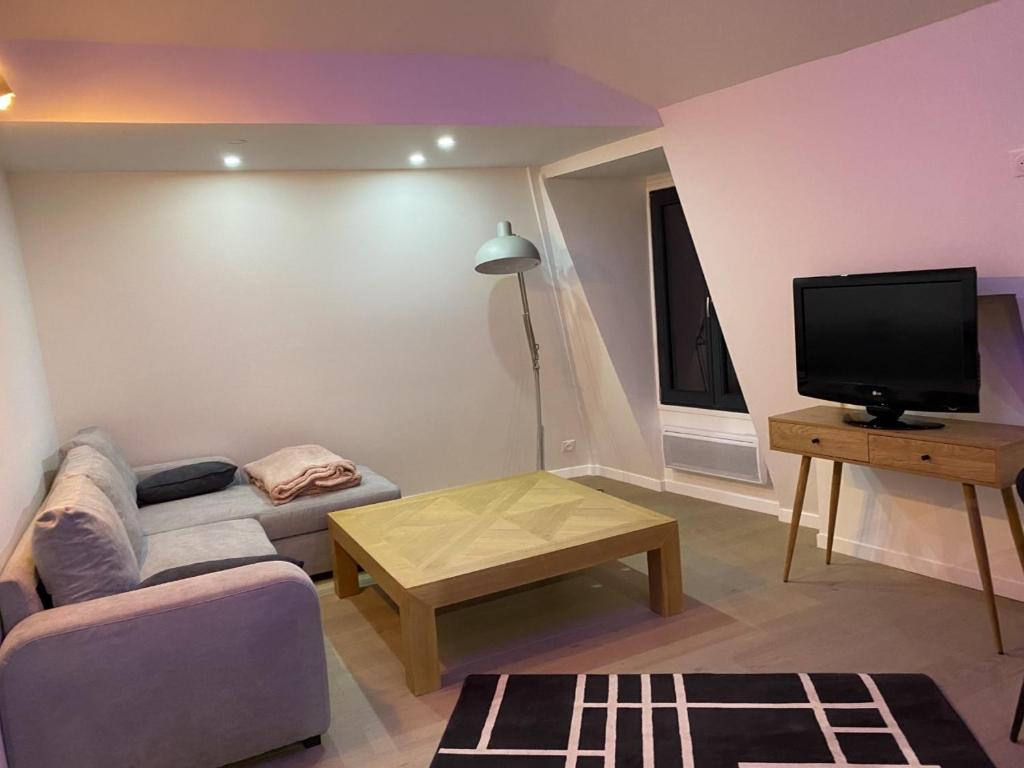 sala de estar con sofá y TV en Super appartement dans le centre de Montmorency en Montmorency