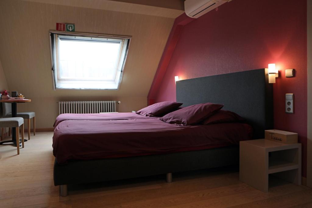 a bedroom with a large bed with a red wall at A Casa in Nieuwpoort