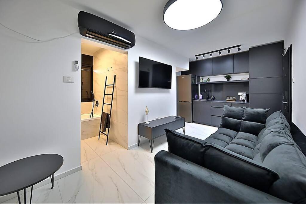un soggiorno con divano nero e tavolo di T'eo 25 suite a Qiryat Yam