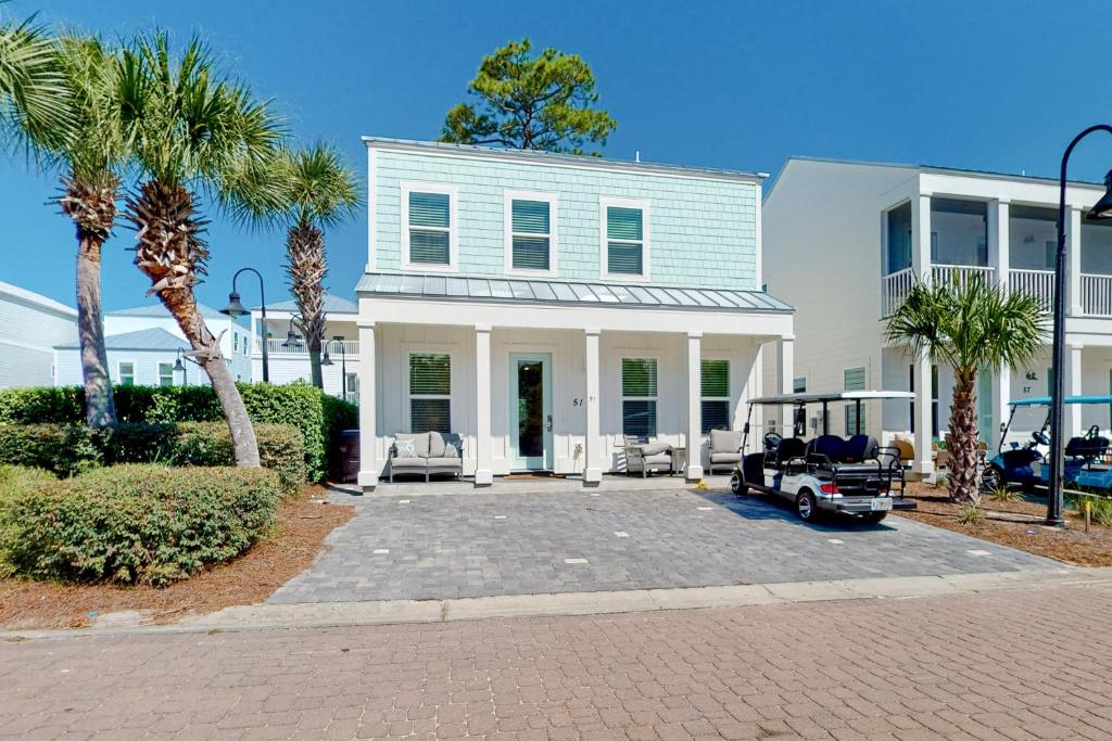 a white house with palm trees and a golf cart at 51 Magical Place in Santa Rosa Beach