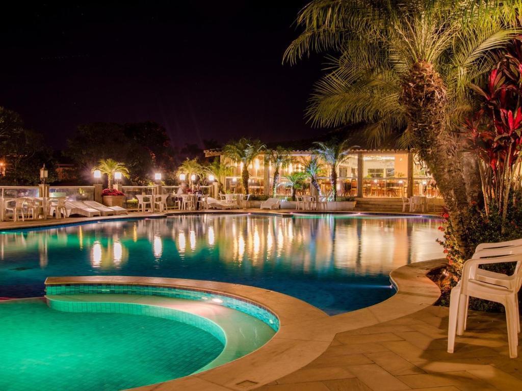 una piscina por la noche con mesa y sillas en Hotel Recanto da Cachoeira, en Socorro