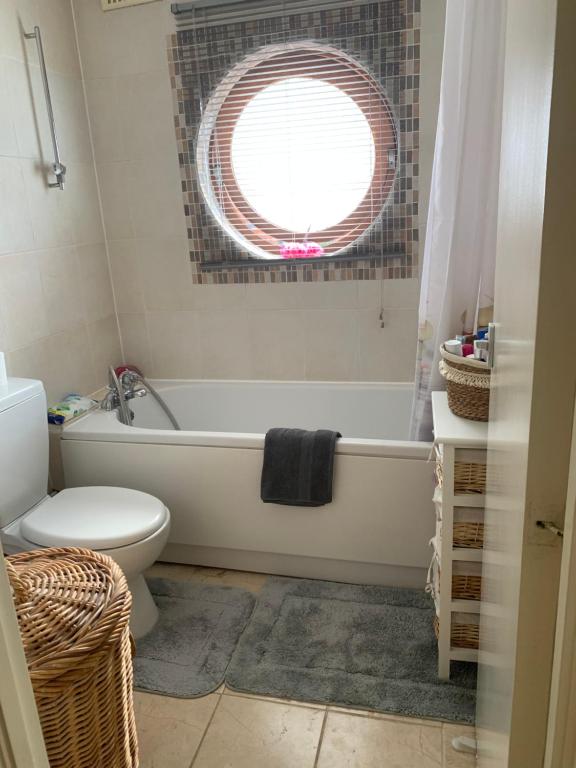 baño con bañera, aseo y ventana en One-bedroom Rotherhithe/Bermondsey flat, Central London, UK, en Londres