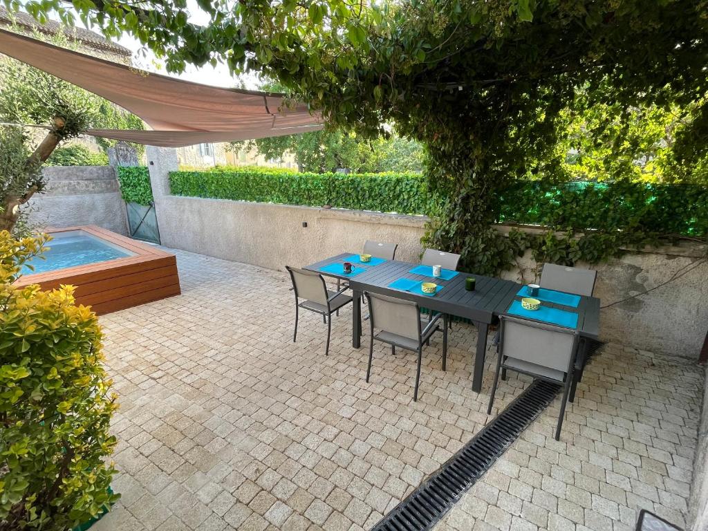 eine Terrasse mit einem Tisch und Stühlen sowie einem Pool in der Unterkunft La maison Mortisson in Saint-Rémy-de-Provence