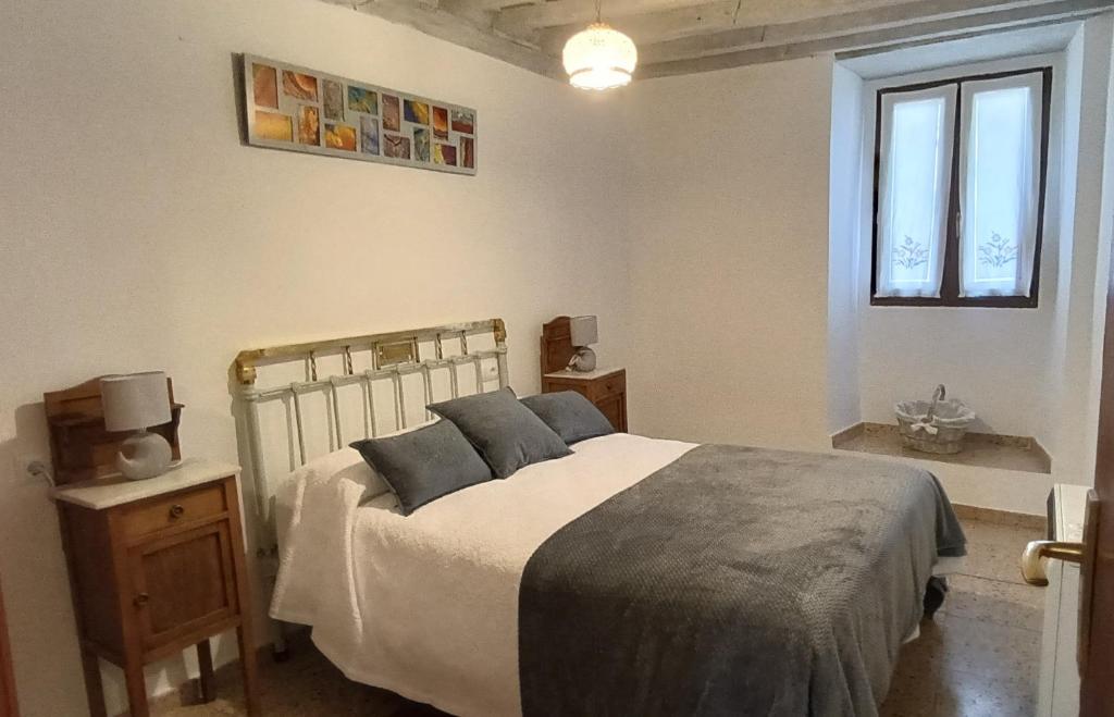 a bedroom with a bed with blue pillows and a window at Casa de la Cigüeña in Candelario