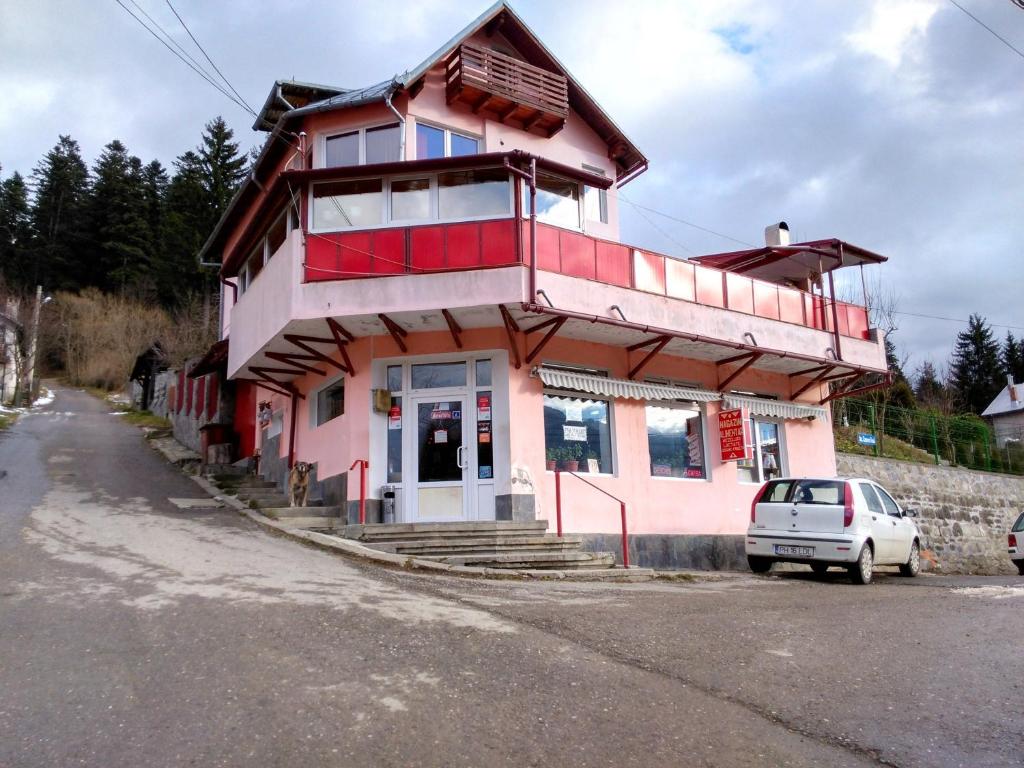 a pink building with a car parked in front of it at Vila Marcela in Buşteni