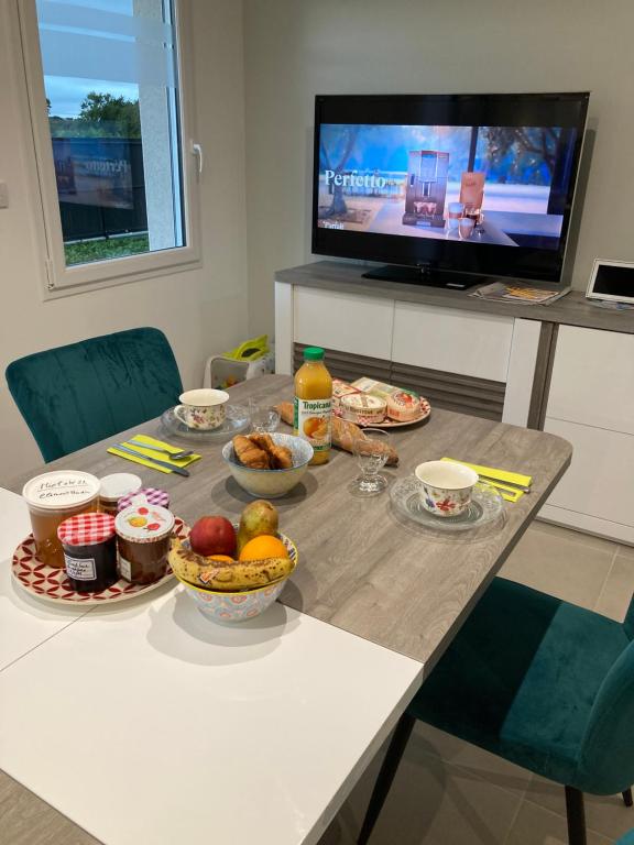 a dining room table with food on it with a television at B&B Sainte Marie du Mont (chambres d’hôtes) in Sainte-Marie-du-Mont