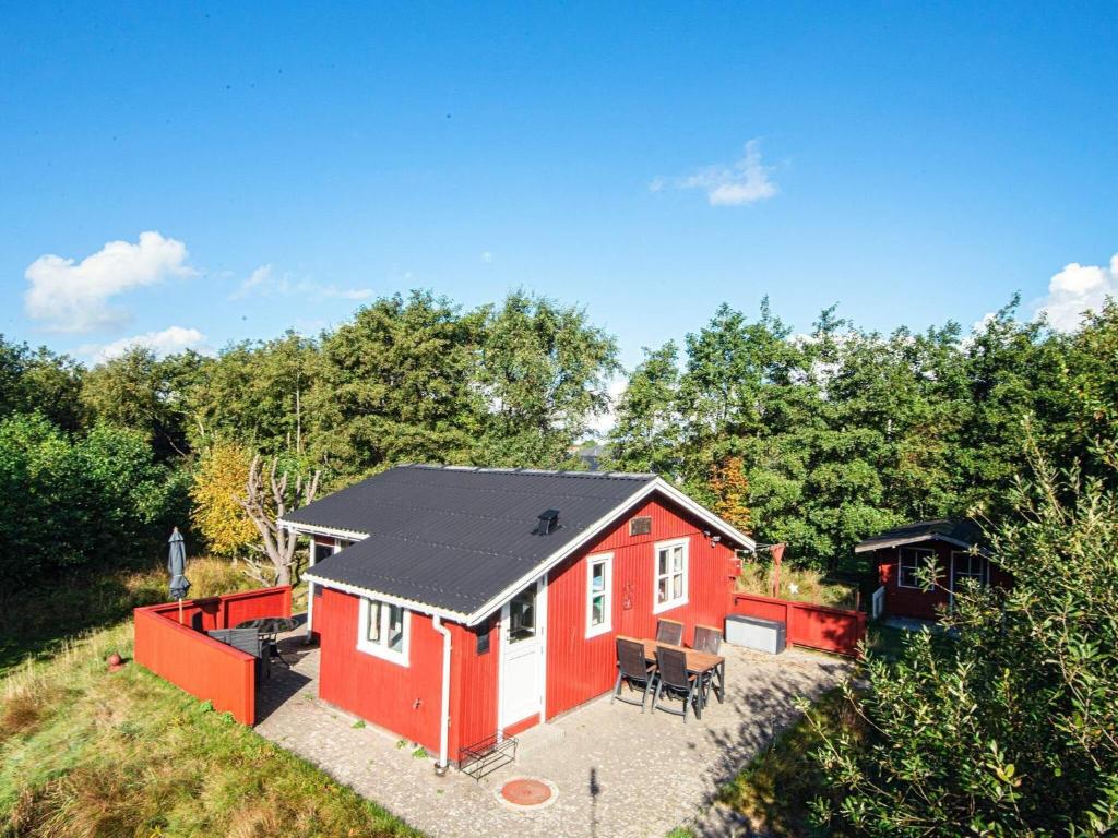 uma casa vermelha com um telhado preto na floresta em 4 person holiday home in Fan em Fanø
