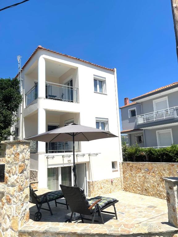a white building with two chairs and an umbrella at Villa Lifestyle & Trends in Limenaria