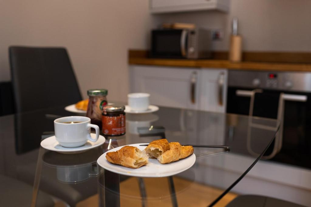 un tavolo con un piatto di prodotti da forno e una tazza di caffè di Quiet Luxury Countryside 2 Bedroom Detached Home a Shudy Camps