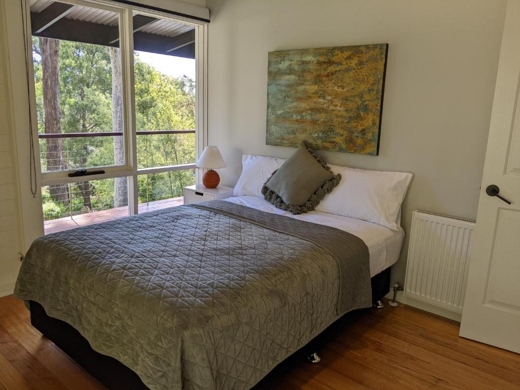 1 dormitorio con cama y ventana grande en Peaceful country home in a middle of a rainforest, en Cockatoo