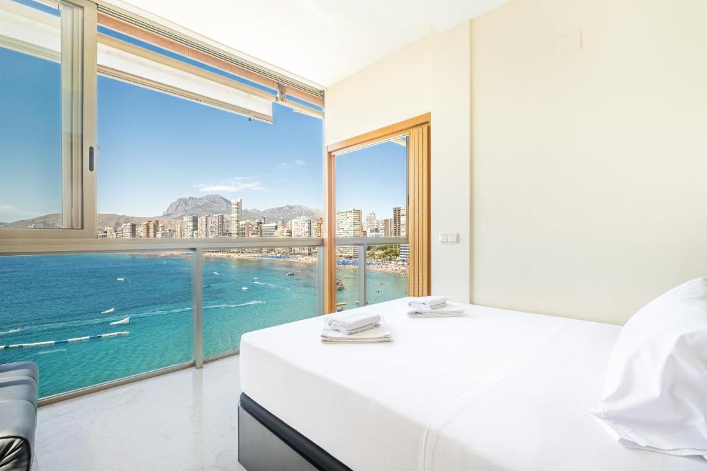a bedroom with a white bed and a large window at Paraiso Lido Sea Views 1-D Levante Beach in Benidorm