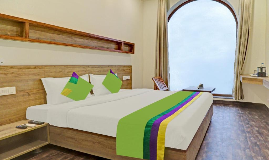 - une chambre avec un grand lit et une couverture colorée dans l'établissement Treebo Trend Delmont, à Chandigarh