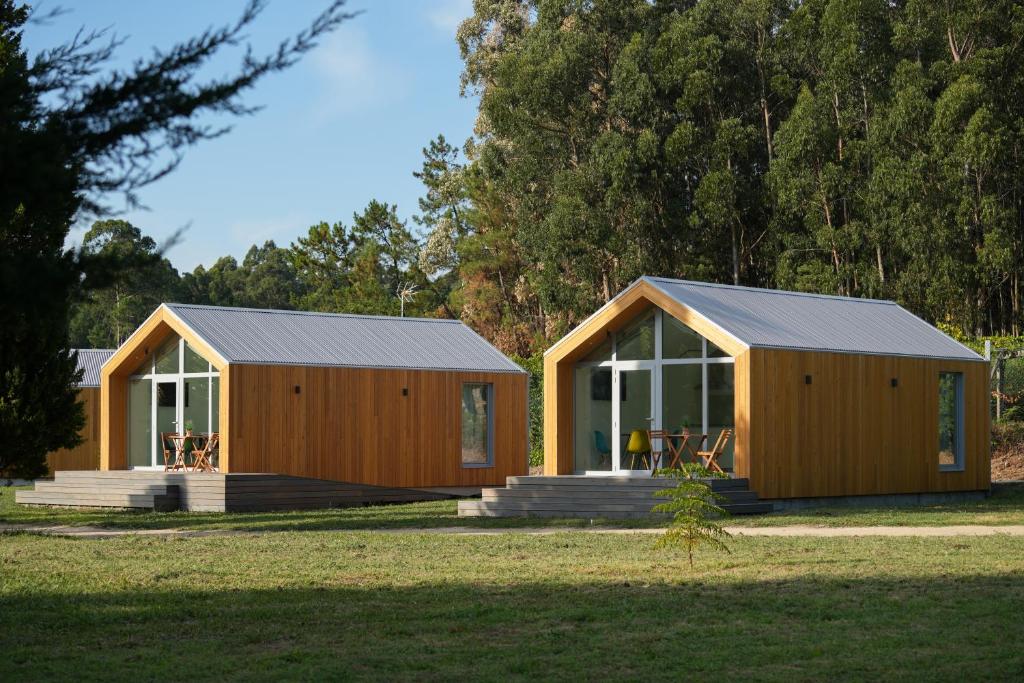 two wooden lodges in a field with trees at NaturBatán in Pontevedra