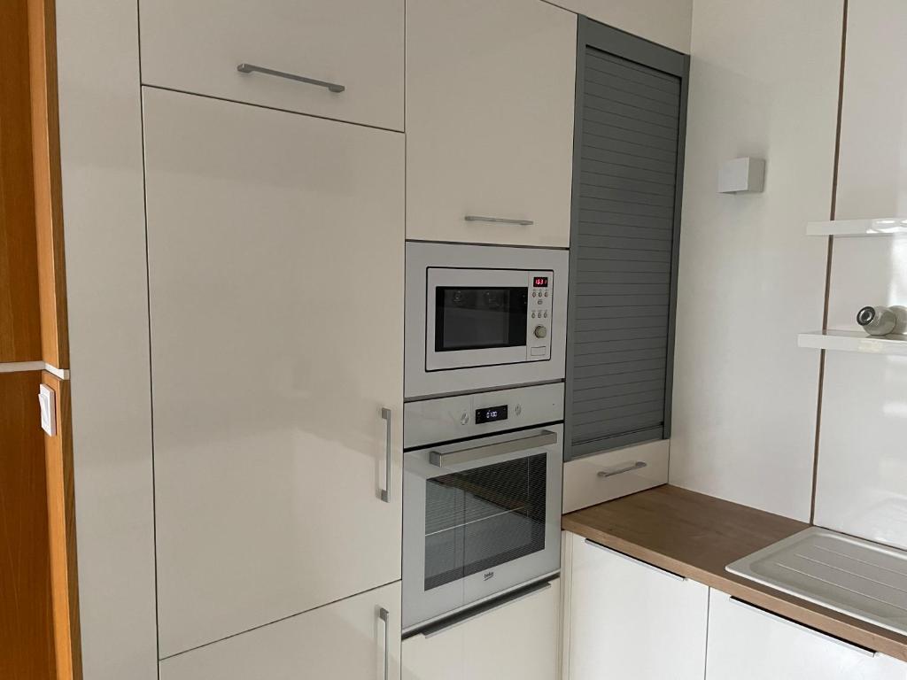kuchnia z białymi szafkami i mikrofalówką w obiekcie Quelle-Apartman w Győr