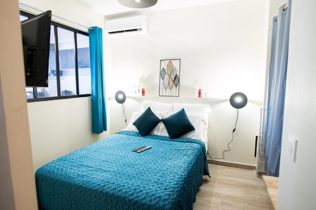 Schlafzimmer mit einem Bett mit blauer Decke in der Unterkunft Le Privilège appartement standing, piscine, terrasse, jardin, parking privé in Cayenne