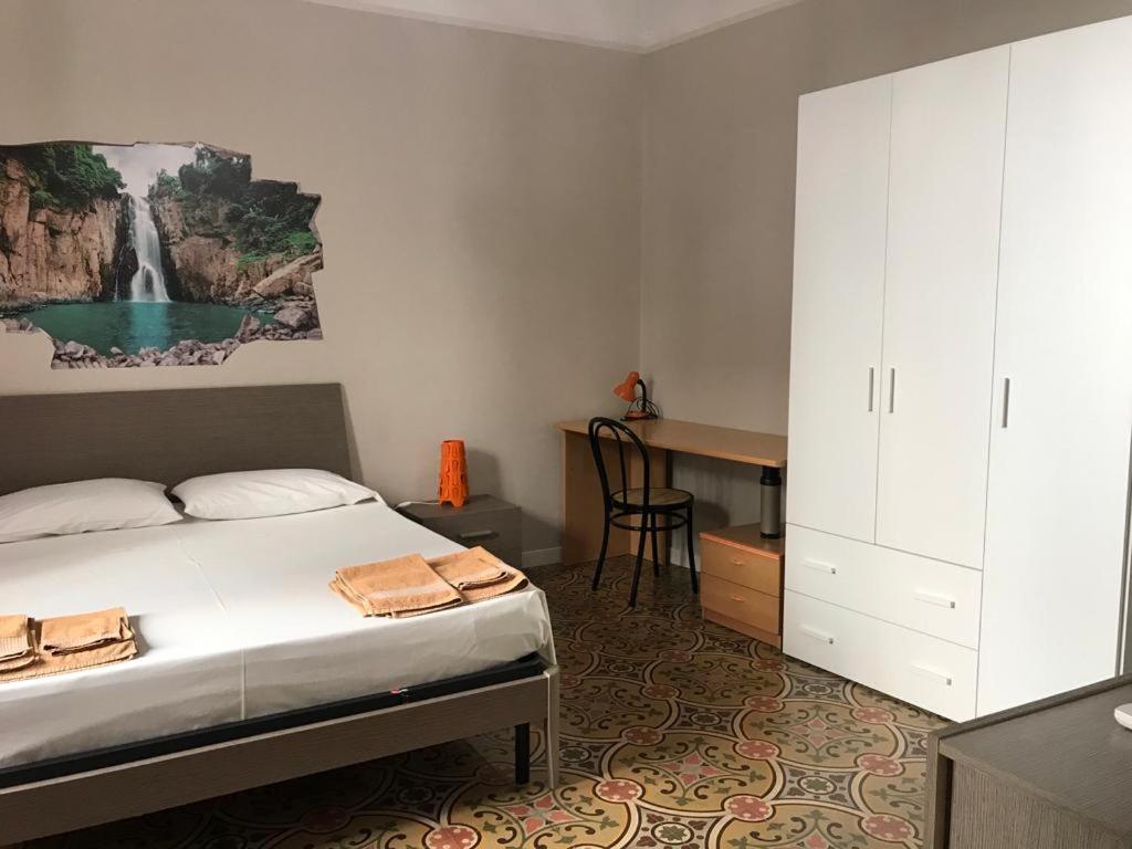 トラーパニにあるAppartamento La Cementinaのベッドルーム1室(ベッド1台、ウォーターフォール絵画のあるデスク付)