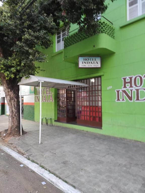 un edificio verde con un cartel delante en Hotel Indaiá en Governador Valadares