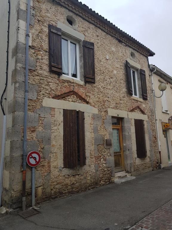 un vieux bâtiment en briques avec des fenêtres et un panneau d'interdiction de stationnement dans l'établissement La Demeure, à Gabarret