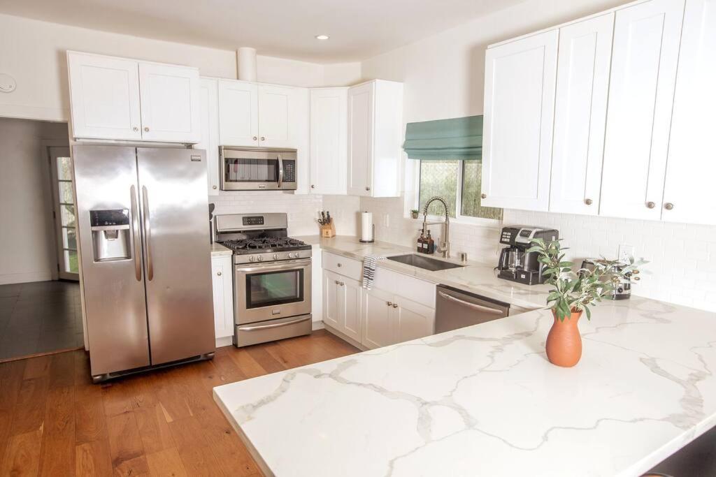 a kitchen with white cabinets and a stainless steel refrigerator at Mid Century Modern - Walk to Dodger Stadium, DTLA in Los Angeles