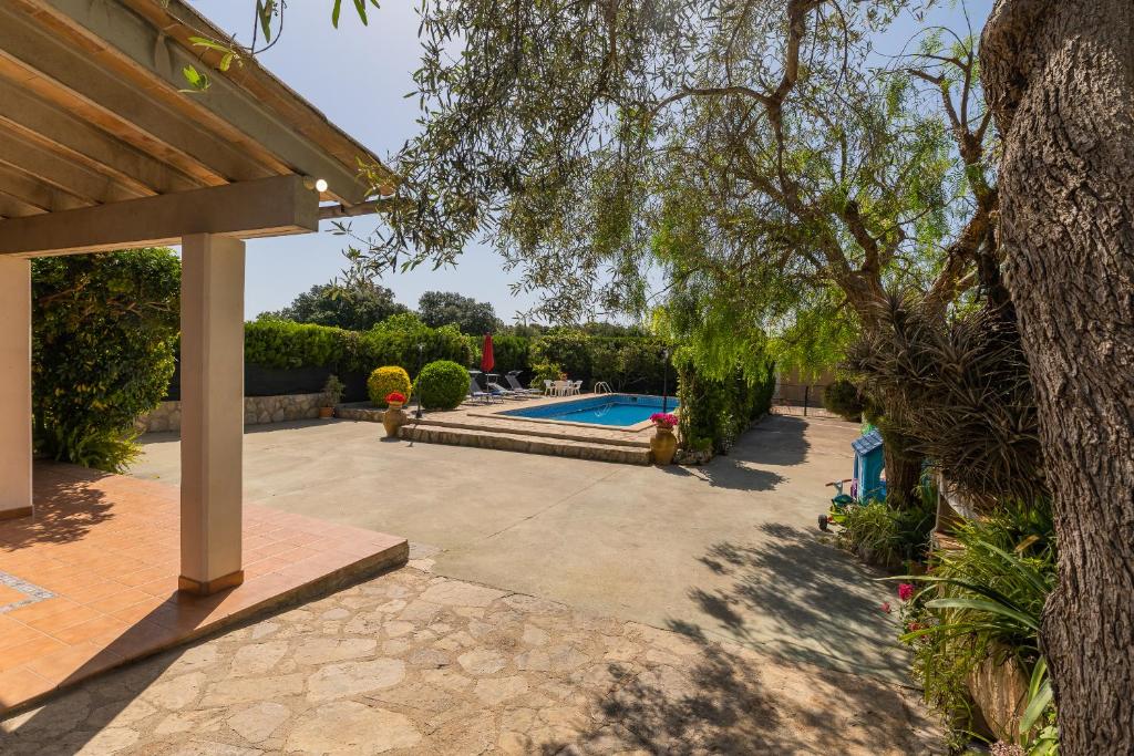 un patio trasero con piscina y un árbol en FINCA SA SINI en Búger