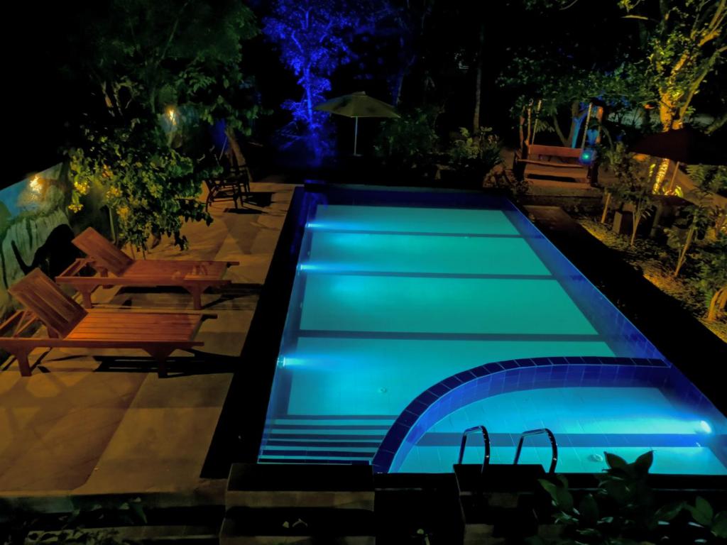 a swimming pool lit up at night at Levona Garden Resort in Habarana
