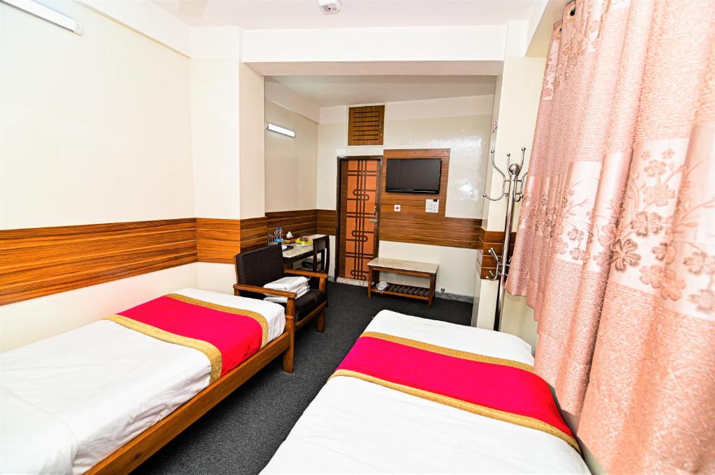 ダッカにあるThe Shahin Residenceのベッド2台とテレビが備わるホテルルームです。