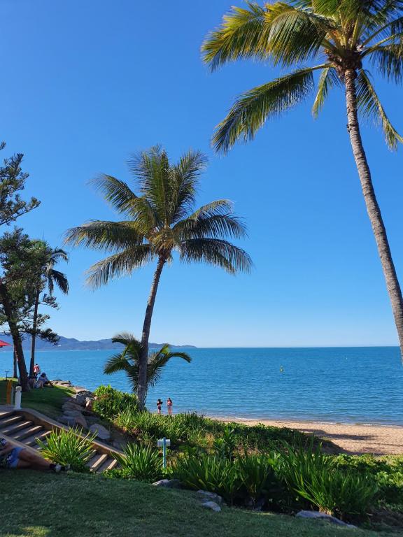 two palm trees on a beach with the ocean at Waters Edge The Strand in Townsville
