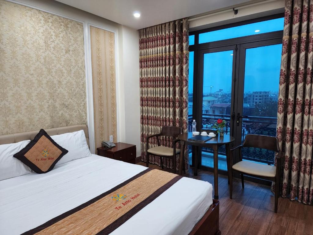 a bedroom with a bed and a table with a view at HOTEL TE AMO in Hai Phong