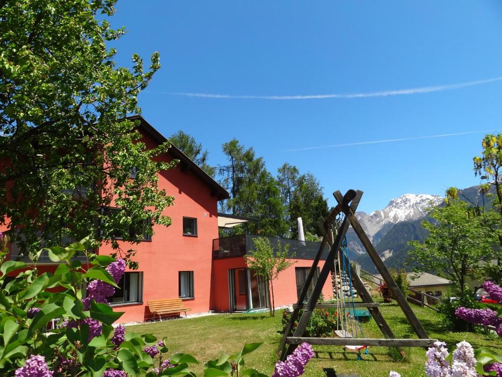 a red house with mountains in the background at Chasa Felix Scuol in Scuol