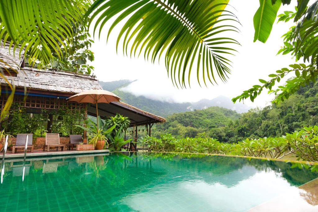 ein Schwimmbad mit einem Haus und Bergen im Hintergrund in der Unterkunft Mandala Ou Resort in Nongkhiaw