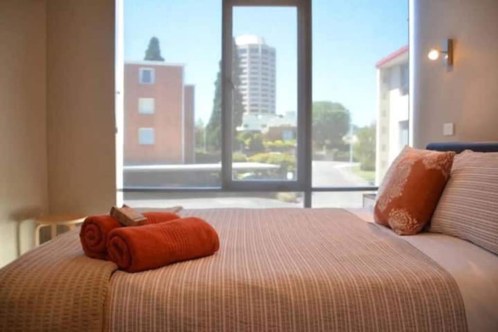 a bed with a towel on it with a large window at Modern 1 bed-walk Casino riverfront 5 mins to CBD in Hobart