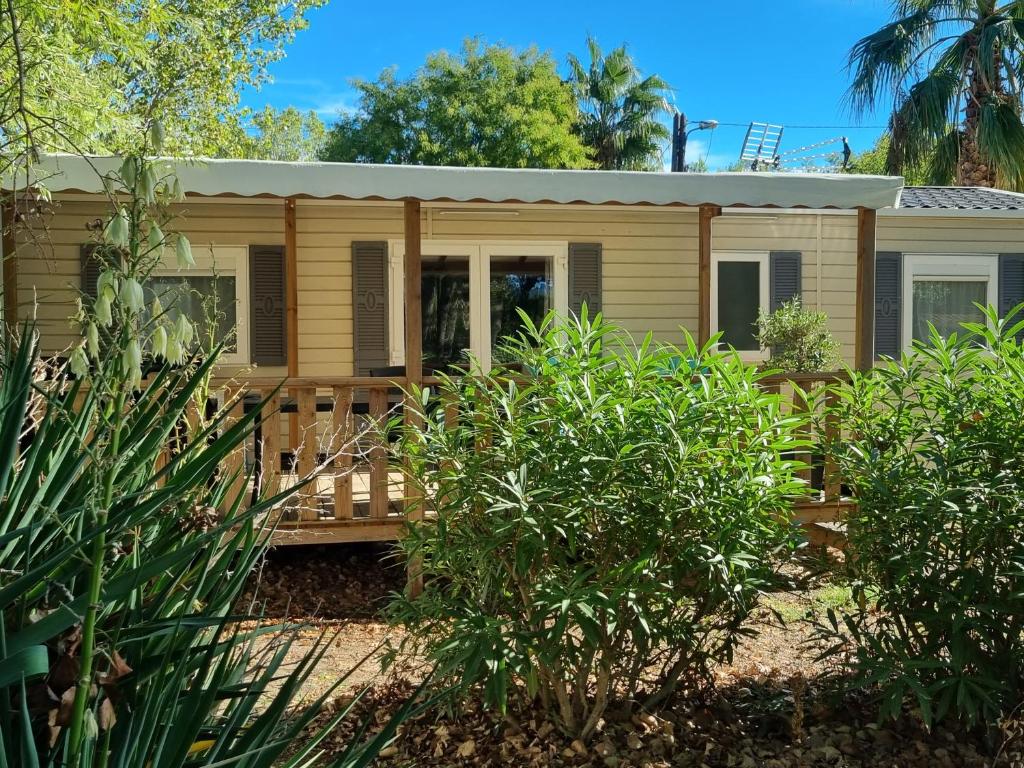 a wooden house with a porch and trees at Mobile home De Luxe St Cyprien in Saint-Cyprien