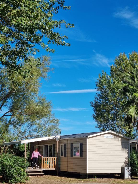 a man standing on the porch of a tiny house at Mobile home De Luxe St Cyprien in Saint-Cyprien