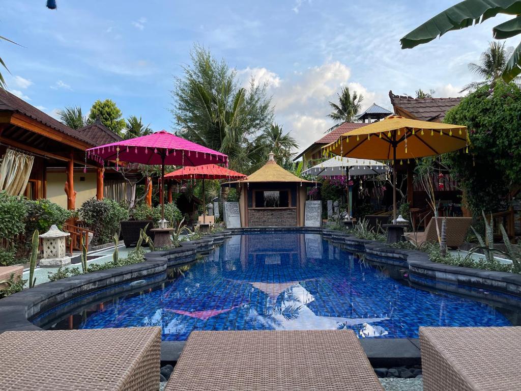 a swimming pool in a resort with umbrellas at Banana cottages in Gili Air