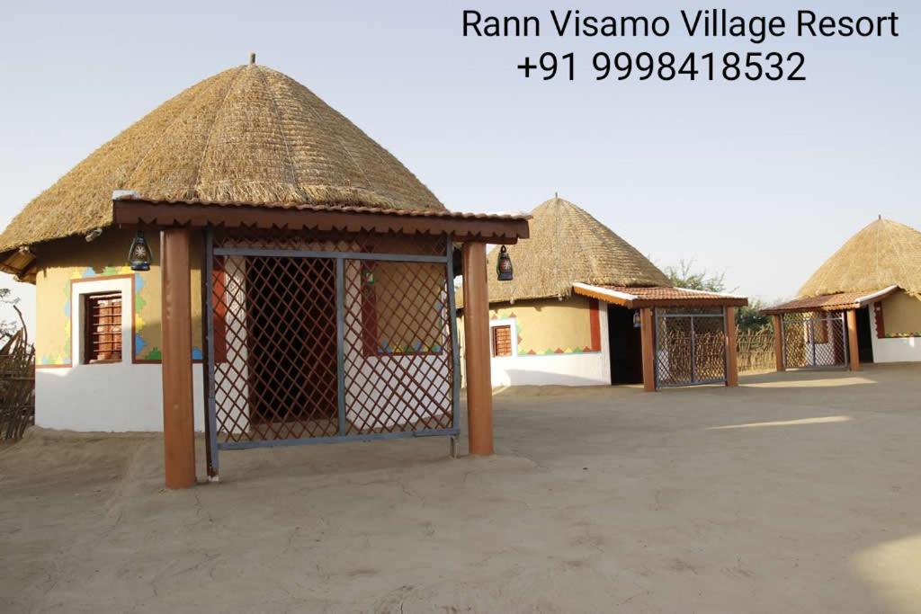 una fila de cabañas con techo de paja en un aparcamiento en Rann Visamo Resort, en Bherandiāla