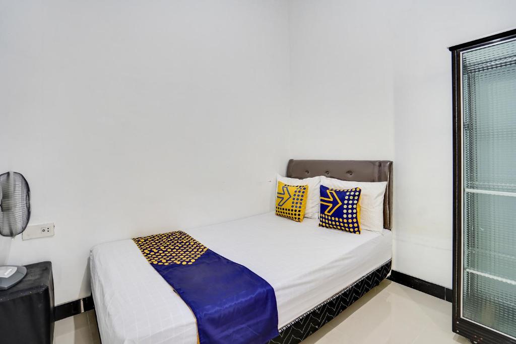 Schlafzimmer mit einem Bett mit blauen und gelben Kissen in der Unterkunft SPOT ON 91745 Rumah Kost Gresik Syariah in Gresik