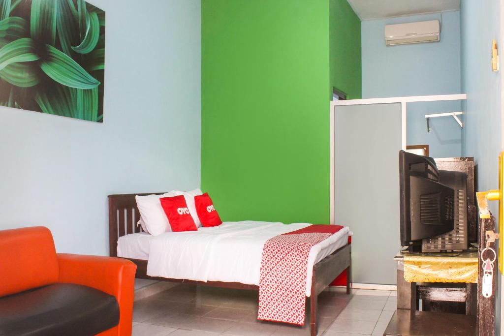 1 dormitorio con 1 cama, TV y sofá en OYO 91769 Wisma Harapan Baik, en Kupang