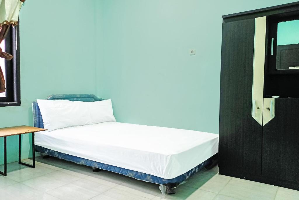 een klein bed in een kamer met een tv bij SPOT ON 91791 Homestay Surya Syariah in Tarakan