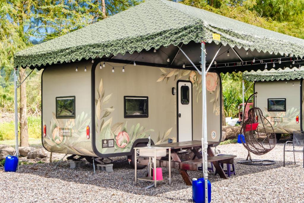 Ta-hsi的住宿－地熱旅居露營車，一个带草屋顶的小露营拖车