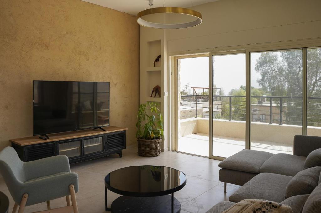 sala de estar con TV, sofá y mesa en סיני 48 מלון דירות בוטיק en Vered Yeriho